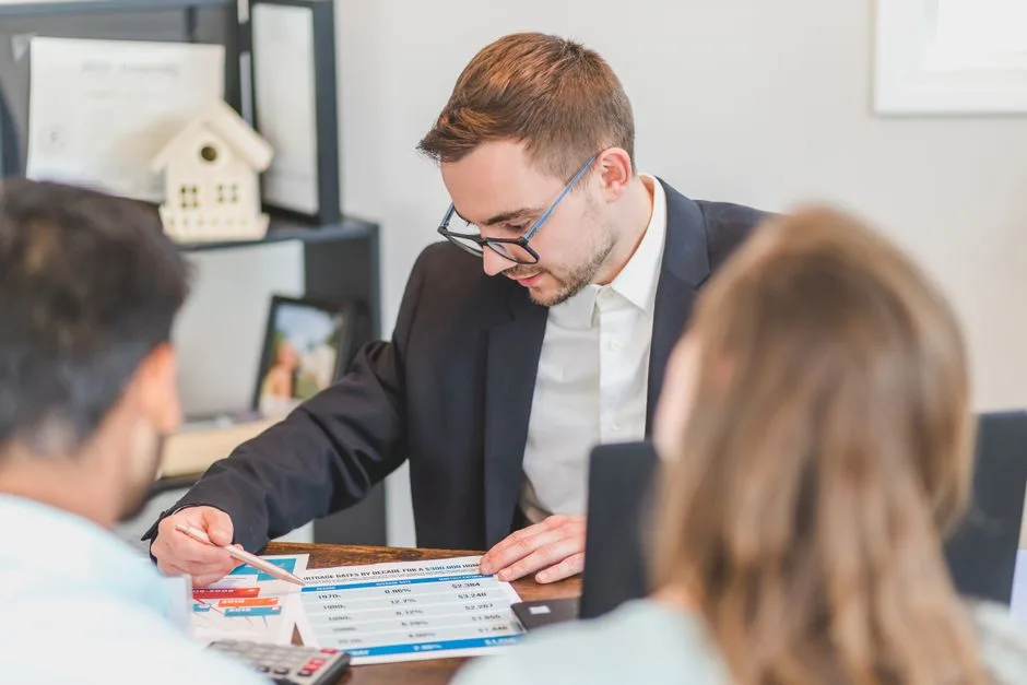 Couple relisant un contrat de prêt immobilier et une délégation d'assurance emprunteur sur la table du salon